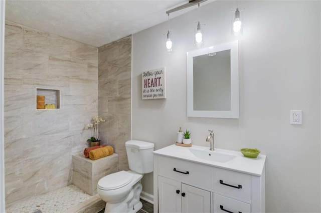 bathroom featuring vanity, toilet, and a tile shower