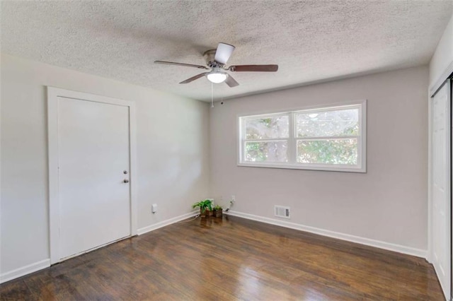 empty room featuring a textured ceiling, dark hardwood / wood-style floors, and ceiling fan