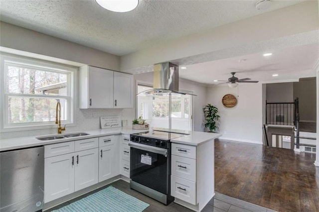 kitchen with island exhaust hood, electric range, sink, and white cabinets