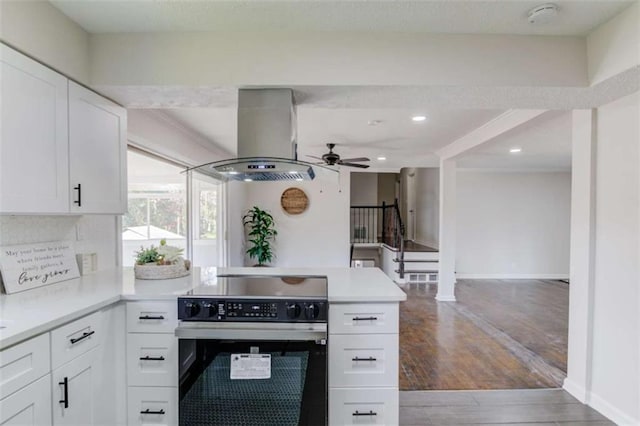 kitchen with stainless steel electric range, ceiling fan, white cabinetry, wood-type flooring, and island exhaust hood