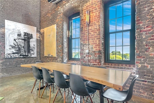 dining room featuring brick wall, a high ceiling, and plenty of natural light