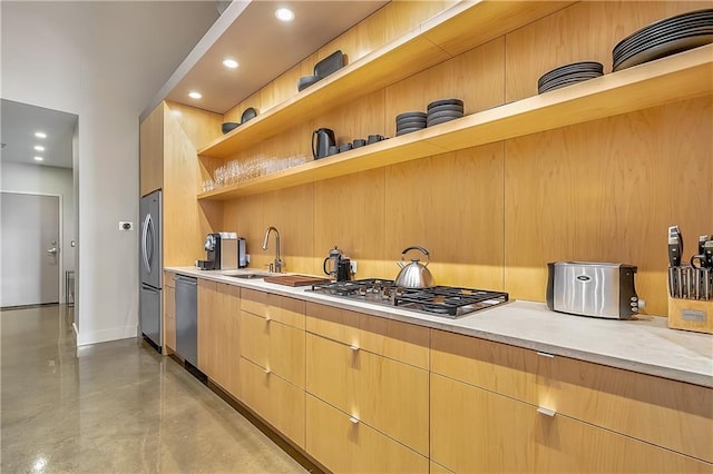 kitchen featuring wooden walls, light brown cabinets, stainless steel appliances, and sink