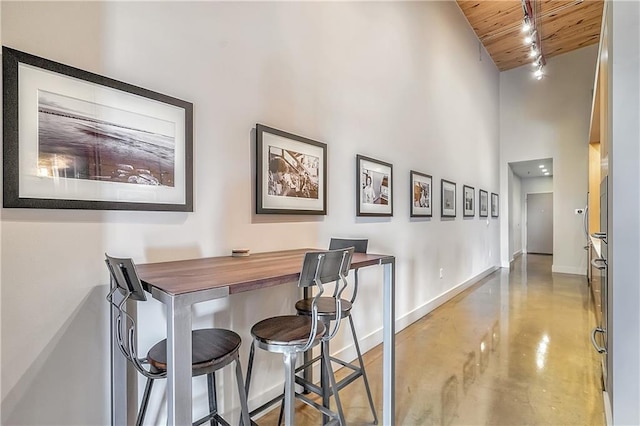 dining space with track lighting, high vaulted ceiling, and wooden ceiling