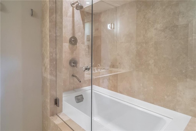 bathroom with shower / bath combination with glass door and tile walls