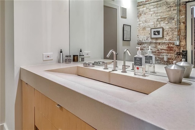 bathroom with vanity and brick wall