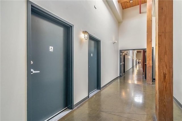 corridor featuring a towering ceiling and beamed ceiling