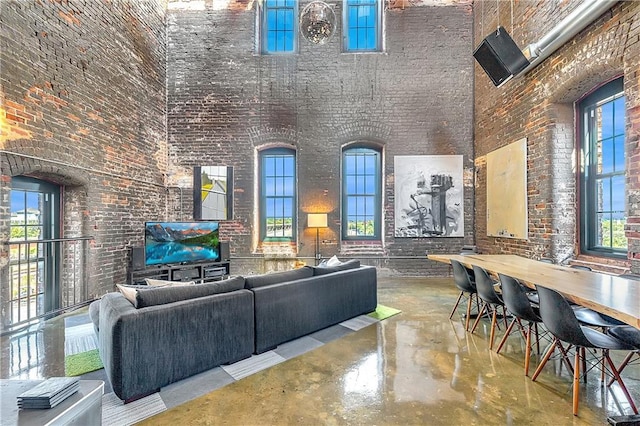 interior space featuring brick wall, concrete floors, and a high ceiling