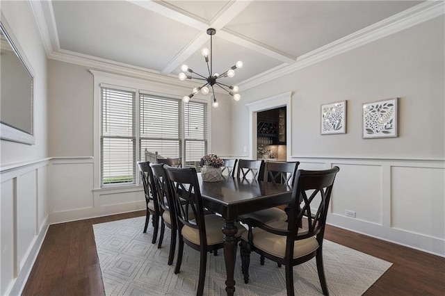 dining space featuring wood finished floors, an inviting chandelier, coffered ceiling, and a decorative wall