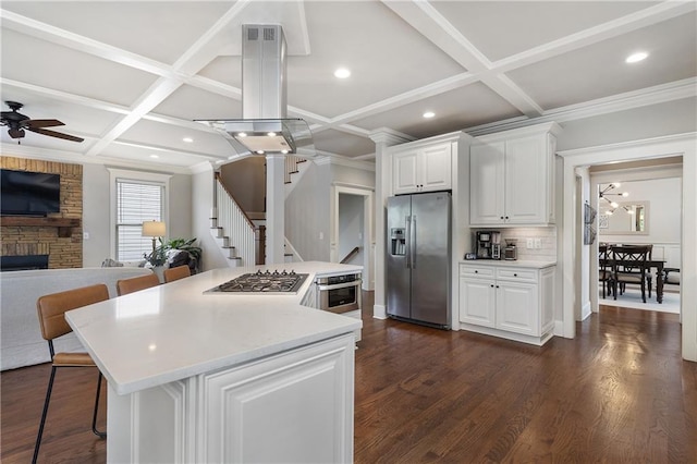 kitchen featuring appliances with stainless steel finishes, open floor plan, a kitchen island, and coffered ceiling