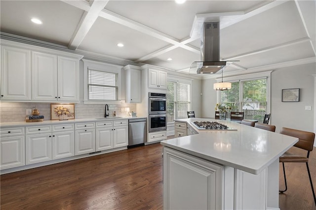 kitchen with white cabinets, coffered ceiling, appliances with stainless steel finishes, and island exhaust hood