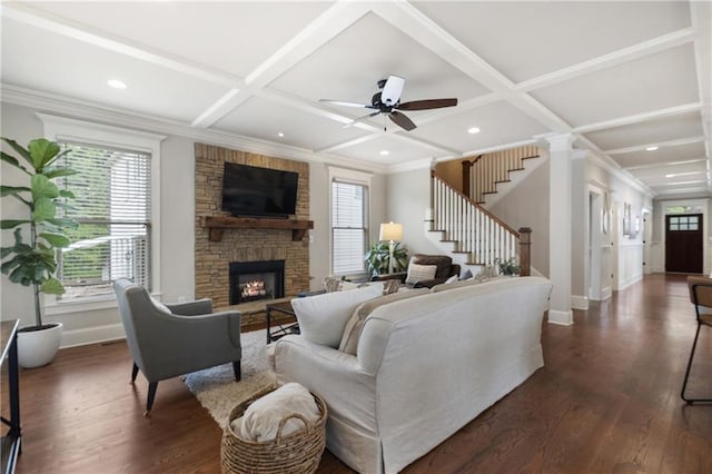 living room featuring stairway, coffered ceiling, a stone fireplace, baseboards, and dark wood finished floors