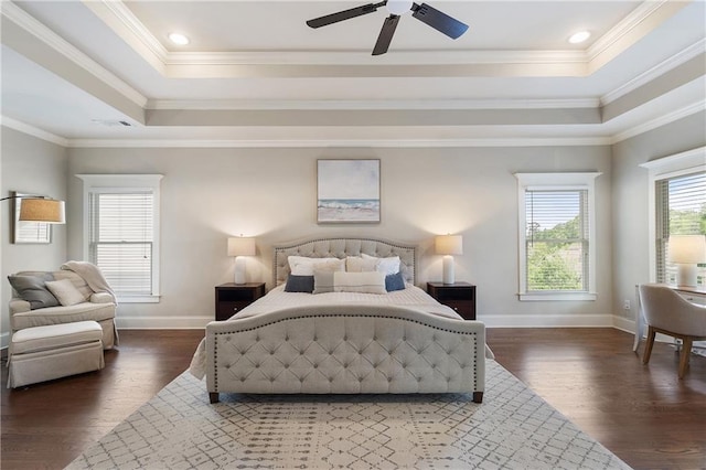 bedroom featuring baseboards, wood finished floors, ornamental molding, and a tray ceiling
