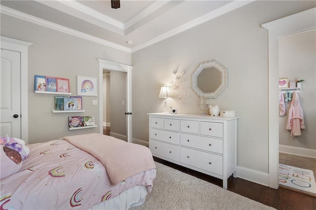 bedroom with dark wood-type flooring, a tray ceiling, ornamental molding, and baseboards