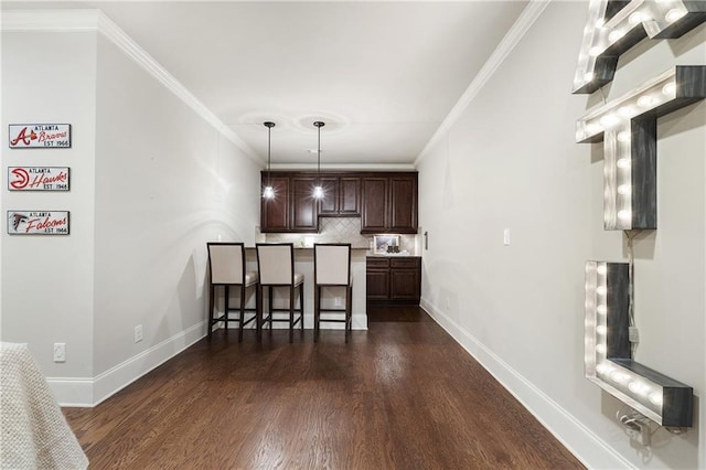 kitchen featuring dark wood-style floors, a kitchen breakfast bar, dark brown cabinets, and tasteful backsplash