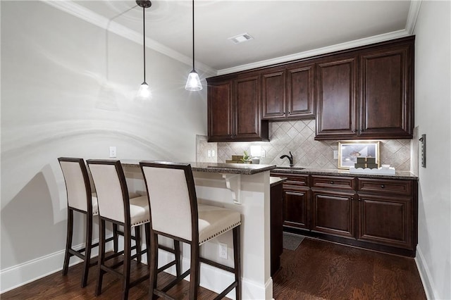 bar featuring pendant lighting, decorative backsplash, crown molding, a sink, and visible vents