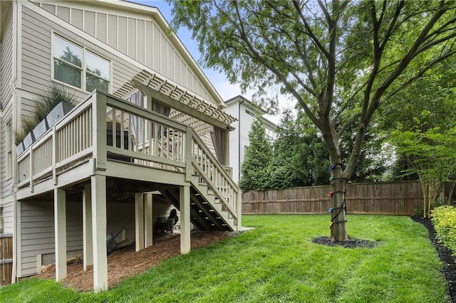 back of house with fence, board and batten siding, a wooden deck, and a yard