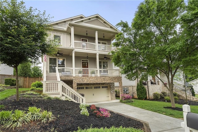 view of front of property with a front lawn, stairs, a ceiling fan, an attached garage, and fence
