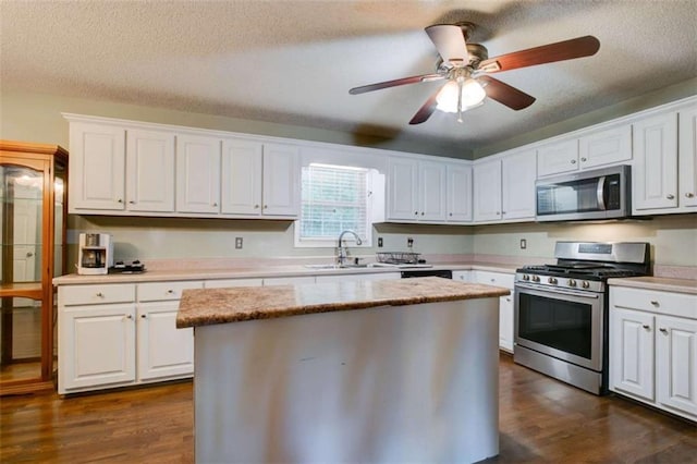1137 Eagles Nest Cir, Carrollton, GA 30116 - kitchen with appliances with stainless steel finishes, white cabinetry, dark wood-style flooring, a textured ceiling, and a center island