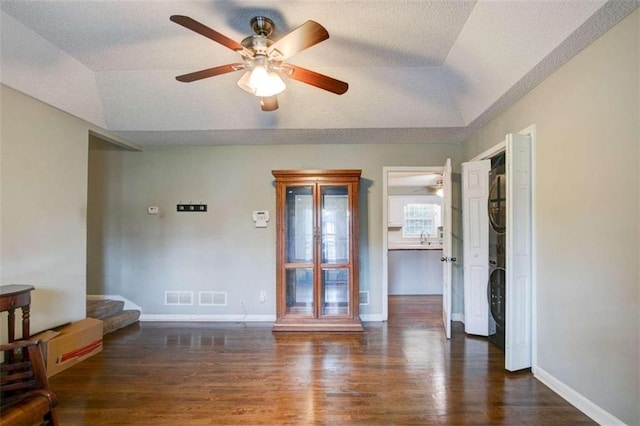 1137 Eagles Nest Cir, Carrollton, GA 30116 - empty room featuring stacked washer / dryer, wood finished floors, ceiling fan, vaulted ceiling, and a tray ceiling