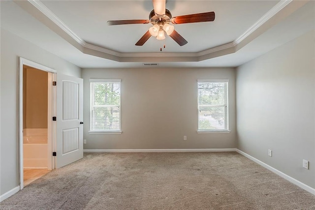 unfurnished room featuring a tray ceiling, crown molding, carpet, ceiling fan, and baseboards