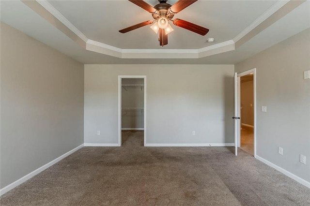 spare room with a tray ceiling, a ceiling fan, baseboards, carpet floors, and ornamental molding
