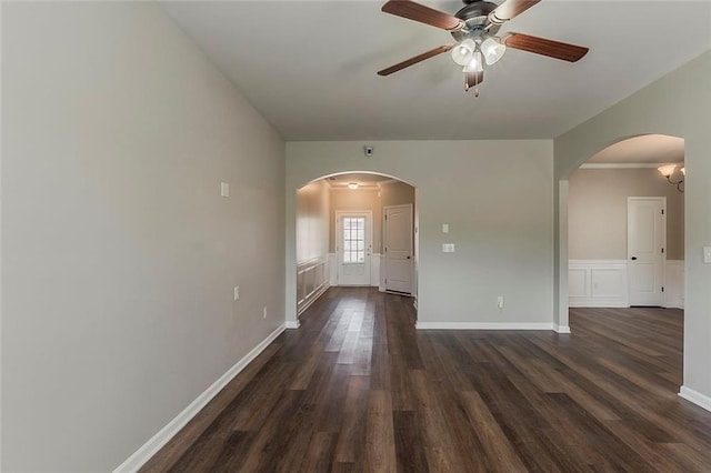 spare room featuring dark wood-style floors, arched walkways, ceiling fan, and baseboards