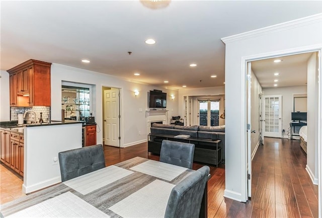 dining room featuring baseboards, dark wood finished floors, recessed lighting, a fireplace, and ornamental molding