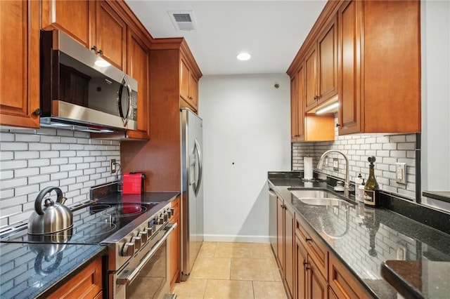 kitchen with visible vents, baseboards, dark stone counters, appliances with stainless steel finishes, and a sink