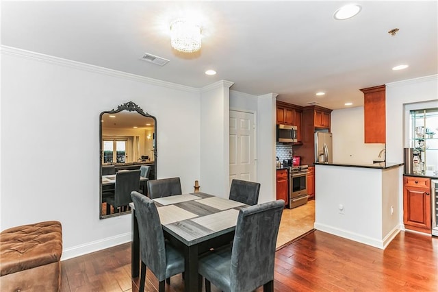 dining room featuring a wealth of natural light, visible vents, hardwood / wood-style floors, and crown molding