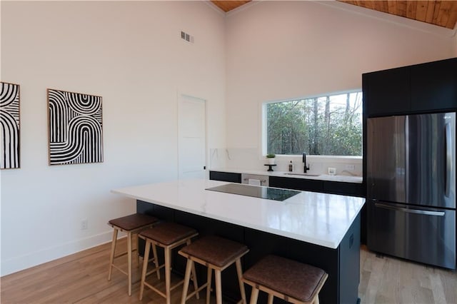 269 Clarice Ln, Sautee Nacoochee, GA 30571 - kitchen with a sink, light wood-type flooring, visible vents, freestanding refrigerator, and a kitchen bar