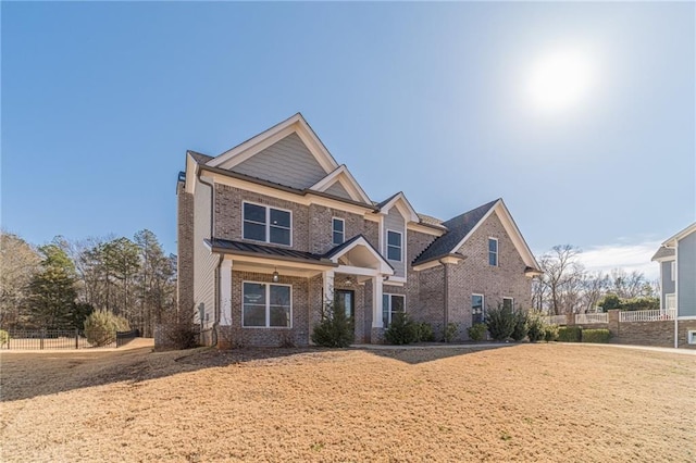 craftsman-style house featuring a standing seam roof, fence, metal roof, and brick siding