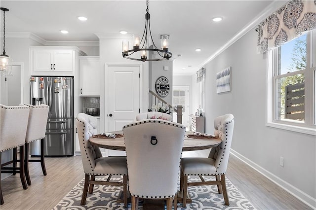 dining area with ornamental molding, a notable chandelier, and light hardwood / wood-style flooring