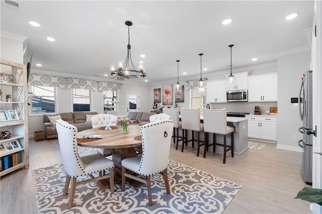 dining room with crown molding, a chandelier, and light hardwood / wood-style flooring