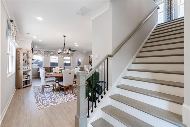 stairs with an inviting chandelier, hardwood / wood-style flooring, and ornamental molding