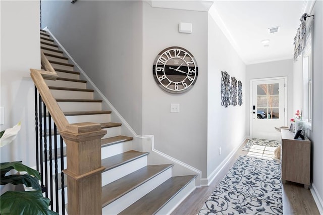 stairway with ornamental molding and hardwood / wood-style floors