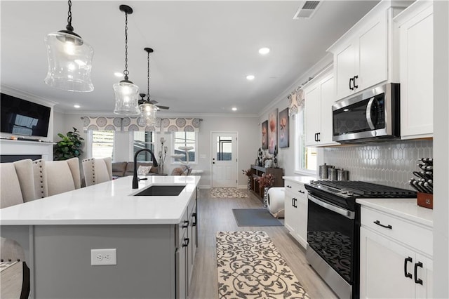 kitchen featuring sink, white cabinetry, appliances with stainless steel finishes, a kitchen breakfast bar, and a kitchen island with sink