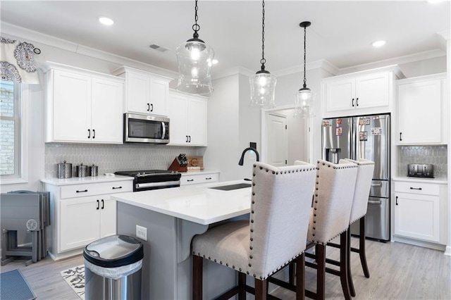 kitchen featuring stainless steel appliances, sink, white cabinets, and decorative light fixtures