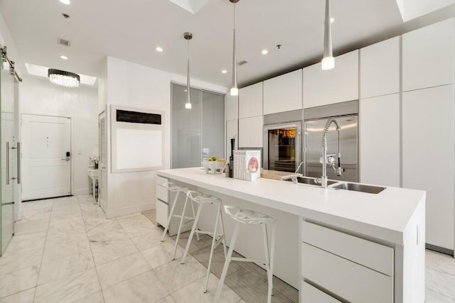 285 Centennial Olympic Park Dr NW Unit Ph2-7, Atlanta, GA 30313 - kitchen with modern cabinets, a sink, white cabinetry, a large island with sink, and light countertops