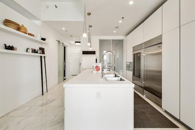 285 Centennial Olympic Park Dr NW Unit Ph2-7, Atlanta, GA 30313 - kitchen with stainless steel built in fridge, a barn door, a sink, white cabinets, and a kitchen island with sink