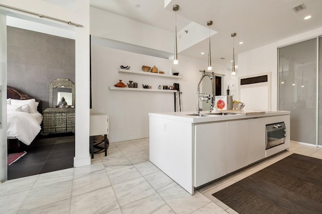 285 Centennial Olympic Park Dr NW Unit Ph2-7, Atlanta, GA 30313 - kitchen with a sink, a kitchen island with sink, decorative light fixtures, light marble finish floors, and white cabinets