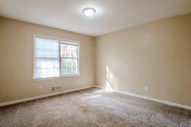 carpeted empty room featuring a textured ceiling