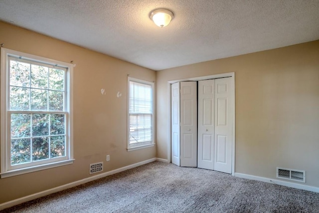 unfurnished bedroom with a closet, carpet, and a textured ceiling