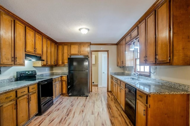 kitchen featuring light stone counters, crown molding, sink, black appliances, and light hardwood / wood-style floors