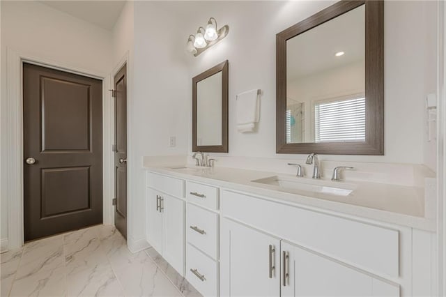 bathroom with double vanity, marble finish floor, a shower, and a sink