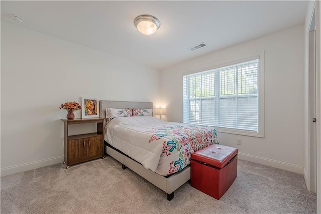 bedroom featuring visible vents, light carpet, and baseboards