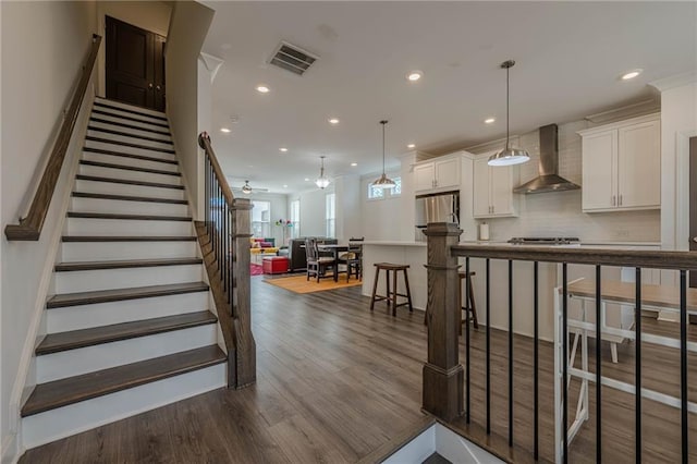 stairway with visible vents, recessed lighting, ceiling fan, and wood finished floors