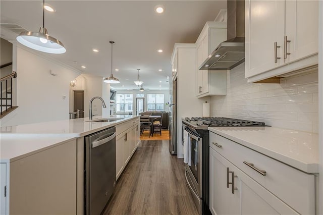 kitchen with a sink, tasteful backsplash, white cabinetry, stainless steel appliances, and wall chimney range hood