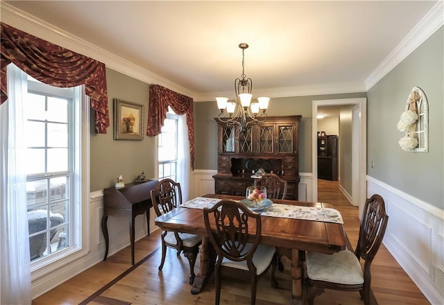 9742 Fallview Ct, Villa Rica, GA 30180 - dining area with a chandelier, a decorative wall, a wainscoted wall, light wood-style floors, and ornamental molding