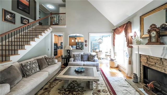 9742 Fallview Ct, Villa Rica, GA 30180 - living area with a fireplace, wood finished floors, stairs, a chandelier, and high vaulted ceiling