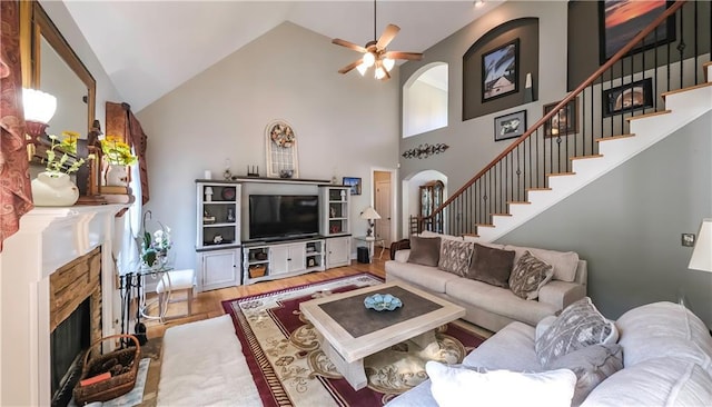 9742 Fallview Ct, Villa Rica, GA 30180 - living area featuring a stone fireplace, wood finished floors, stairway, a ceiling fan, and high vaulted ceiling